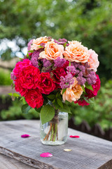 Bouquet of pink and apricot garden roses on wooden table