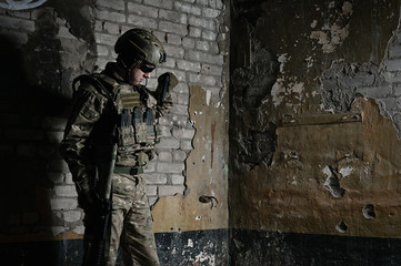 Man in camouflage standing against brick wall