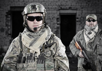 Men with rifle standing against brick wall
