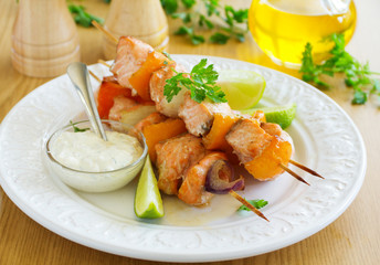 Shashlik of salmon with vegetables and white sauce.