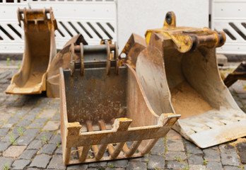 Rostbraune Baggerschaufeln am Strassenrand auf einer Baustelle