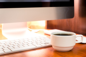 Cup of coffee and PC on wooden desk