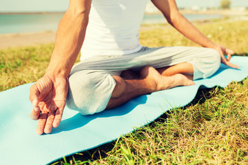 Obraz na płótnie Canvas close up of man making yoga exercises outdoors