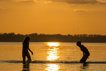 two teen girls have fun bathing in the sea in evening sun