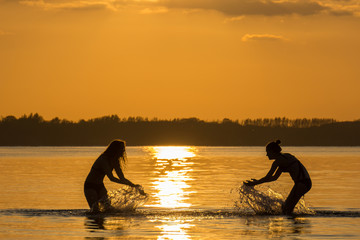 Zwei Teanager baden im Meer bei Sonnenuntergang