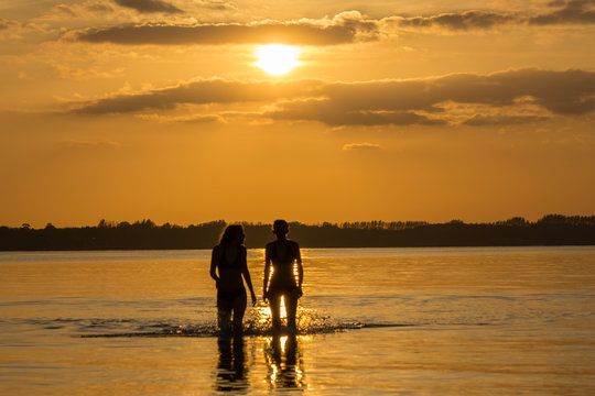 Teanager baden im Meer bei Sonnenuntergang