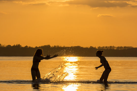Teanager baden im Meer bei Sonnenuntergang