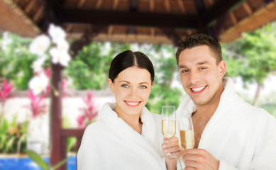 happy couple in bathrobes with champagne at resort