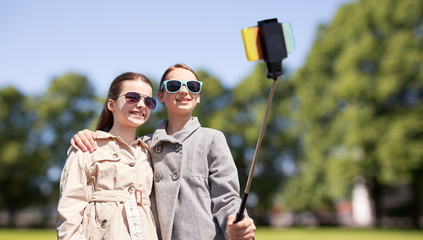 Fototapeta premium happy girls with smartphone selfie stick in park