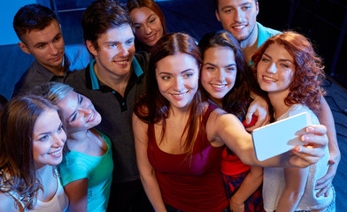 friends with smartphone taking selfie in club