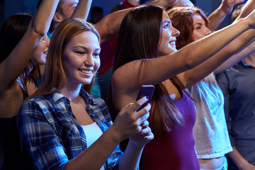 woman with smartphone texting message at concert