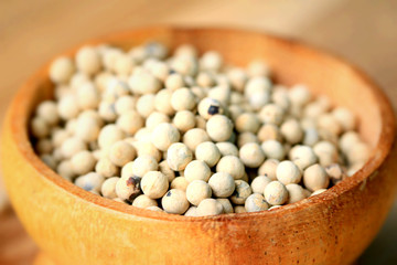 white pepper seeds on wooden background.