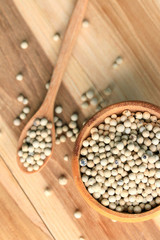 white pepper seeds on wooden background.