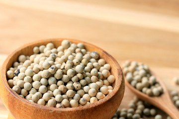 white pepper seeds on wooden background.