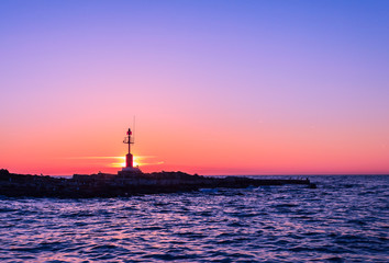 Scenic view of beautiful sunset above the sea with silhouette of island and light house