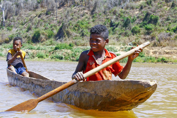 Young Malagasy african boy rowing traditional canoe on river