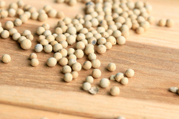 white pepper seeds on wooden background.