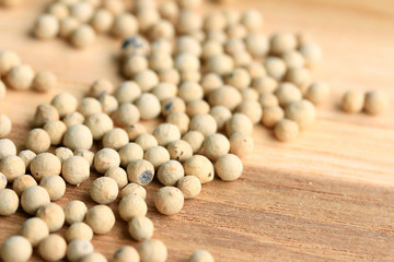 white pepper seeds on wooden background.