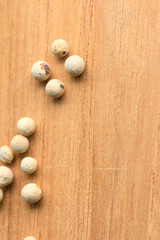 white pepper seeds on wooden background.