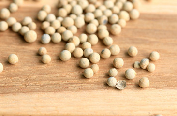 white pepper seeds on wooden background.