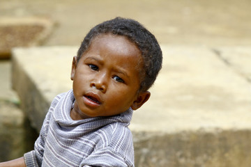 Poor malagasy boy carrying plastic water bucket - poverty