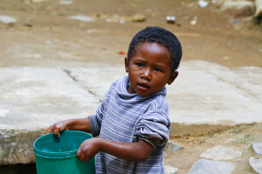 Poor Malagasy Boy Carrying Plastic Water Bucket - Poverty