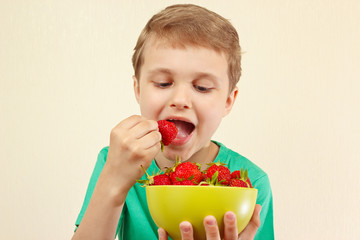 Young boy eating fresh strawberries from a bowl