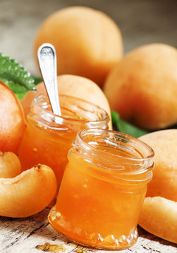 Homemade apricot jam and fresh apricots with leaves on the old w