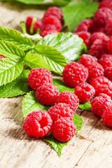 Fresh ripe raspberries with large leaves on the old wooden table