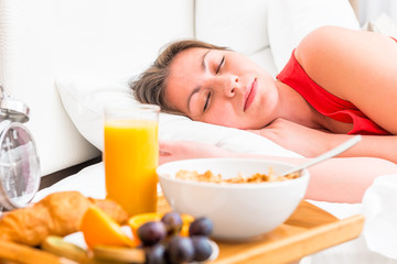 Obraz na płótnie Canvas breakfast on a tray beside the bed sleeping girl
