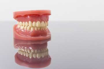 Set of artificial lower and upper jaw false teeth viewed low angle across a wooden table with copyspace
