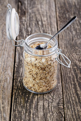 The oat flakes in jar on wooden table.