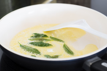 Closeup of Fresh Sage Leaves Being Fried with Butter in a Ceramic Pan