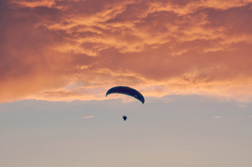 Parachute flyier on pink cloudy sky