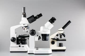 Monocular, binocular and trinocular microscopes on grey backgrou