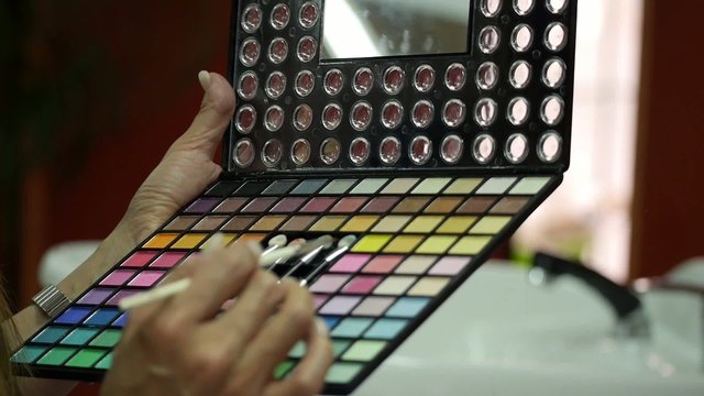 MAQUILLADORA SOMBRA DE OJOS
Plano c&aacute;mara en mano de paleta de sombra de ojos, maquillaje sujeta por una mujer profesional
