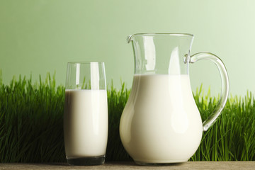 Glass of milk and jar on flower meadow