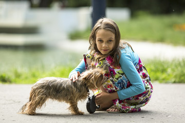 Sweet little girl on the street with a small dog.