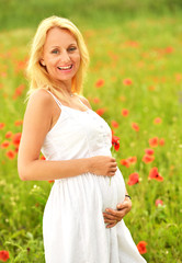 Fototapeta na wymiar Pregnant happy woman in a flowering poppy field