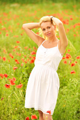Naklejka na ściany i meble Pregnant happy woman in a flowering poppy field