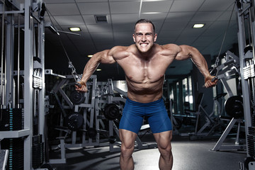 Fototapeta na wymiar Muscular bodybuilder guy doing exercises workout in gym