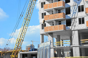 Crane and building construction site against blue sky