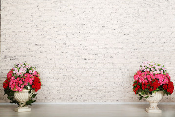 Empty room with white brick wall and beautiful flowers in pots