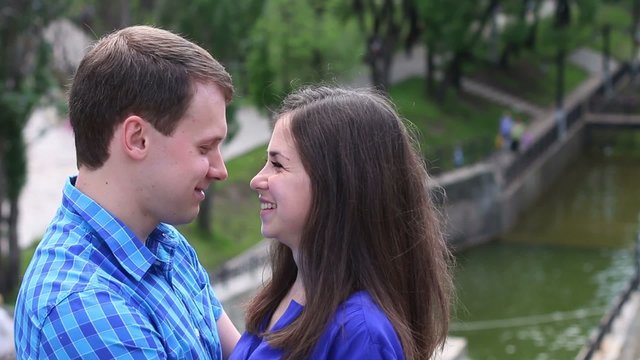 Man and woman look at each other and kiss near small river at summer day

