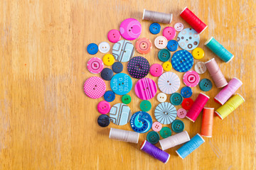 Spools of threads and buttons on  wooden table
