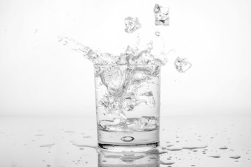 Splashing of water with ice in glass