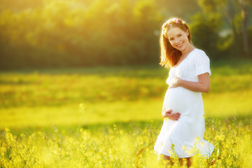 beautiful pregnant woman in summer nature meadow with yellow flo