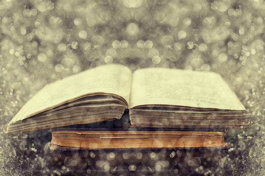 Open old vintage books on wooden background with fantastic double exposure effect using photo of snow bokeh, theme of the reading and education