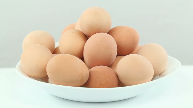 Eggs in a bowl - Boiled chicken eggs stacked up in a white bowl rotating slowly in a seamless loop on white background