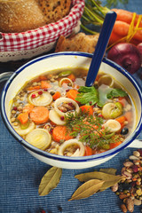Vegetable soup in a metal bowl on a rural rustic wooden table.